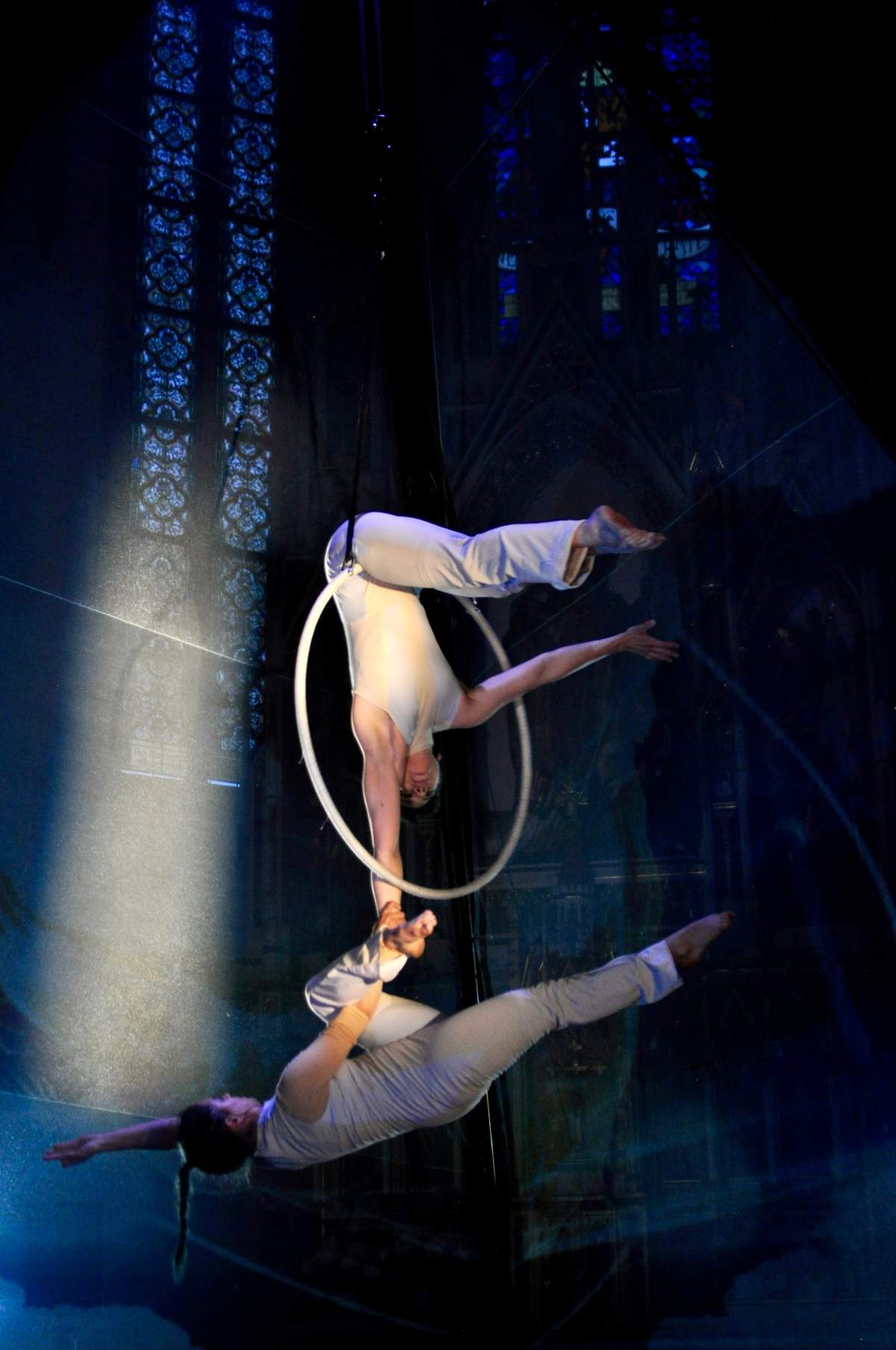 Zwei Artistinnen im Duo am Aerial Hoop vor bunten Kirchenfenstern.