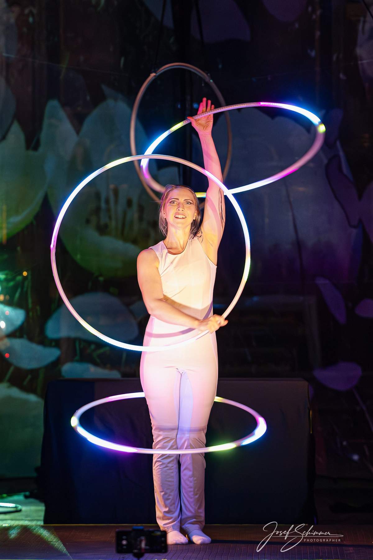 Hula-Hoop-Darbietung mit farbigem Bühnenlicht.