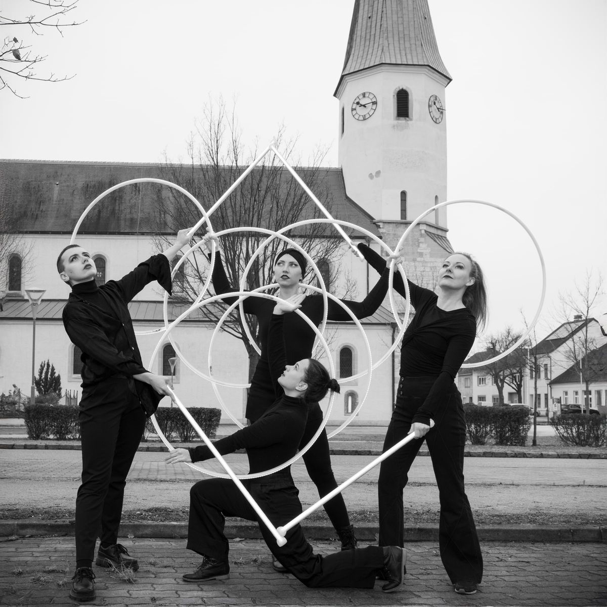Schwarzweißaufnahme des Ensembles vor einem Kirchturm.
