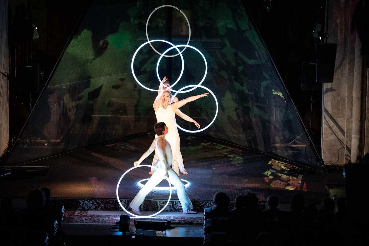 Ensemble mit leuchtenden Hoops vor grün illuminierter Projektion.